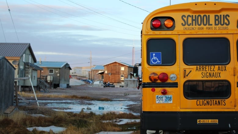 A school bus sits amid grass and snow.