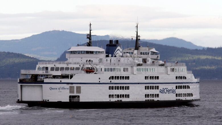 A large, squat, ferry sails on the open sea.