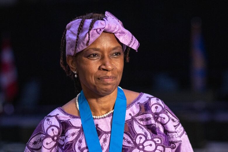 A Black woman wearing a matching purple dress and headpiece