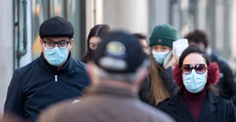 People in masks are pictured walking in Quebec.