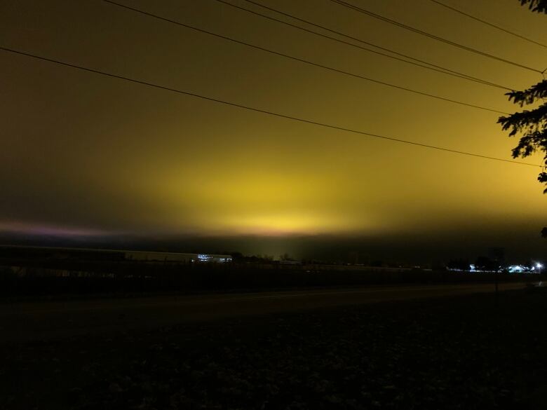 A large golden glow is cast across a night sky