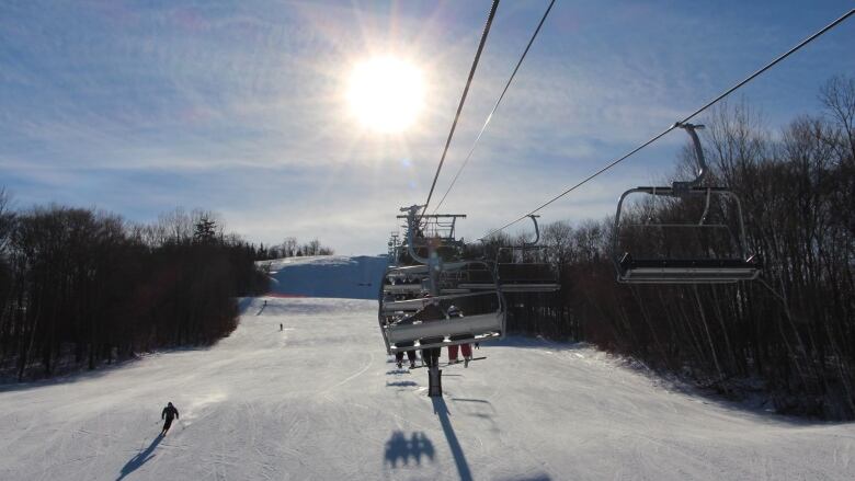 a ski lift suspended above a snowy track with trees on either side