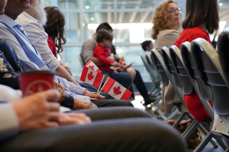 Seated people hold tiny Canadian flags.