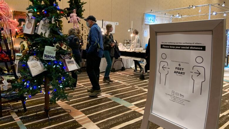 A conference floor with holiday decorations and a sign that tells people to stand six feet apart.