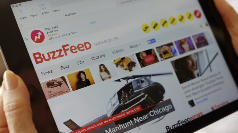 A phone screen is shown, looking at the BuzzFeed website,