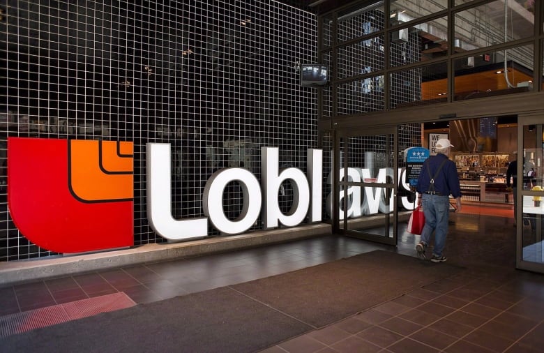 A man carrying a shopping bag walks past a huge sign bearing the words 