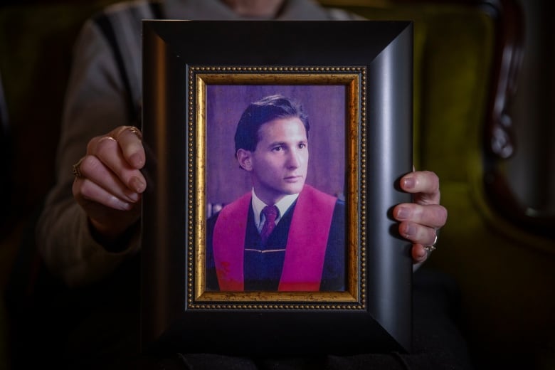 A photo frame held for the camera showing a man in graduation gown.