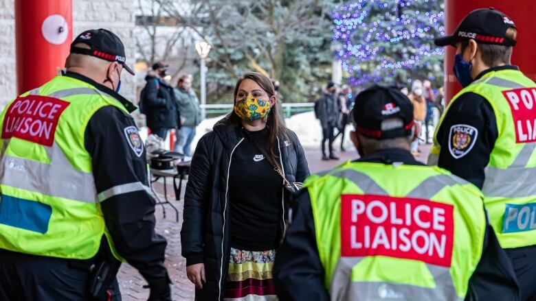 A woman in a mask stands near three men with police liaison vests.