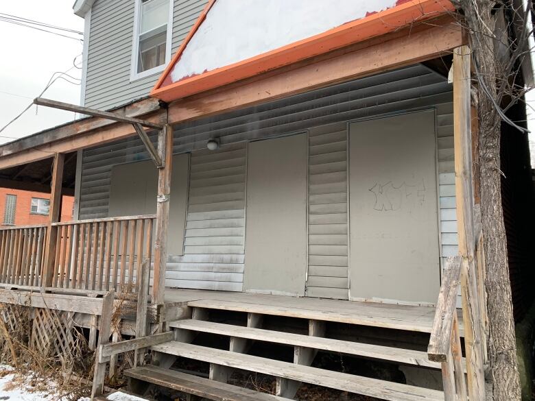 A building sits with boarded up windows. 