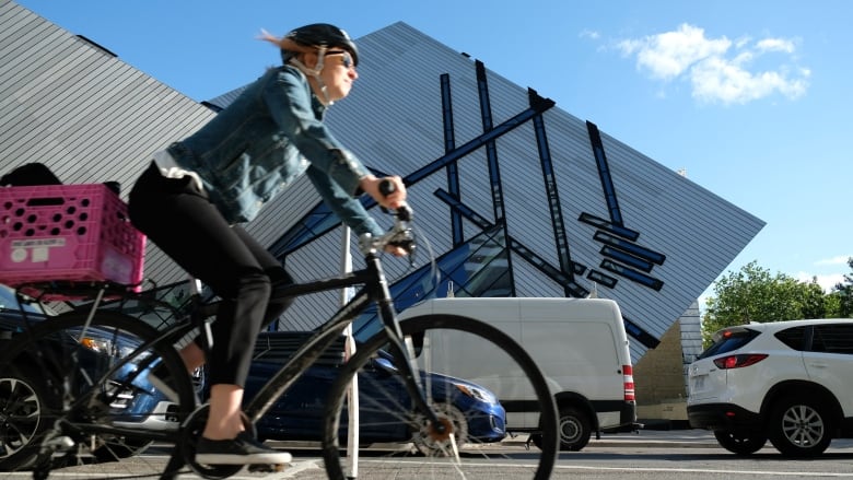 A woman cycles past the Royal Ontario Museum in a protected bike lane on Bloor Street West.