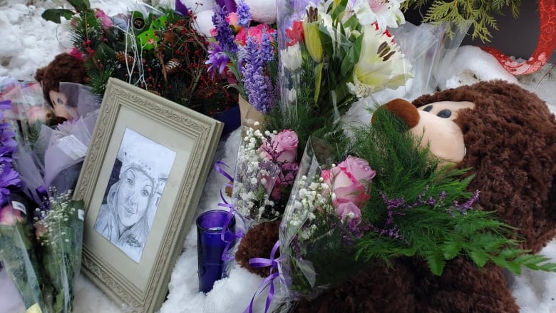 A photo of a young woman in graduation cap in surrounded by flowers, letters and a stuffed bear.