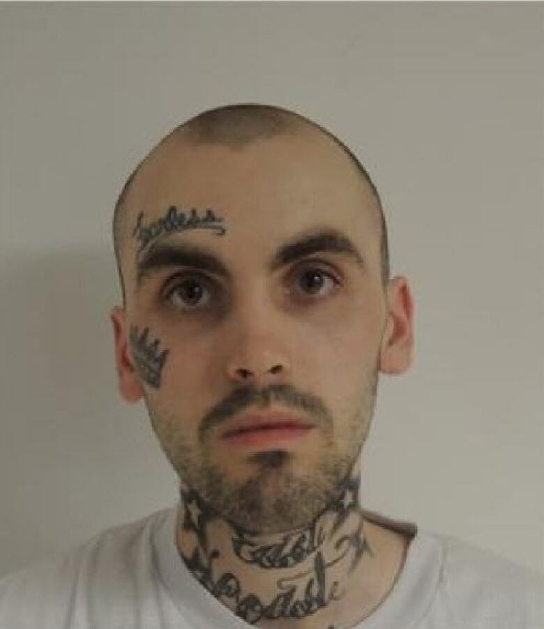 A mugshot of a man with several tattoos on his neck and face.