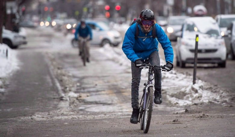 A cyclist rides their bike on a path during winter.