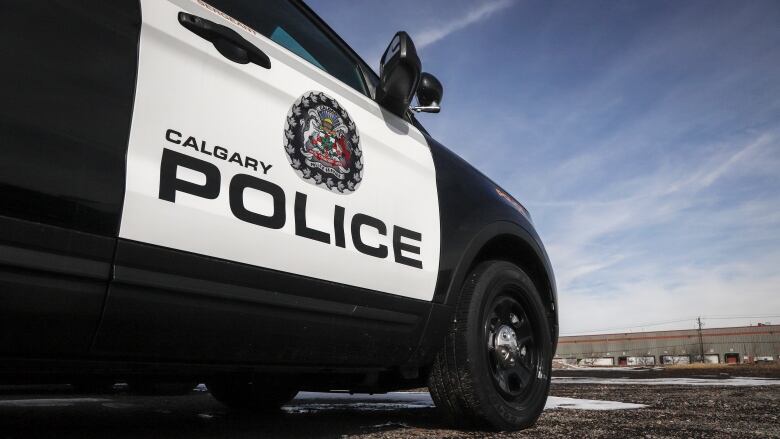 A black and white police car is parked in an empty parking lot. The text on the car reads 'Calgary police'