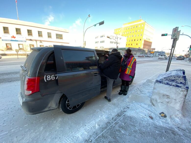 People heading into a black van in winter. 