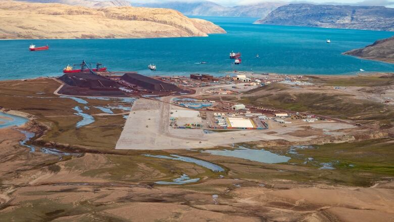 Ships in water in background, land with operations in foreground.