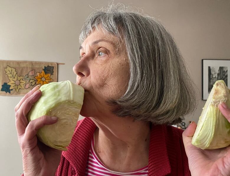 A woman holds a cabbage.