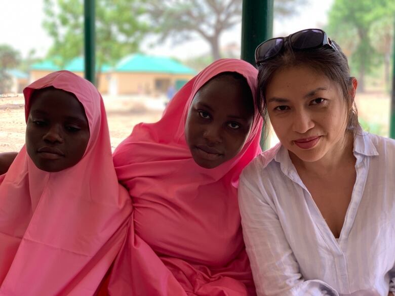 Three women look at the camera as their picture is taken.