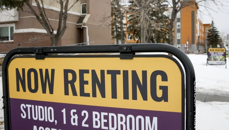 A rental sign is posted in the yard of a brick apartment building.