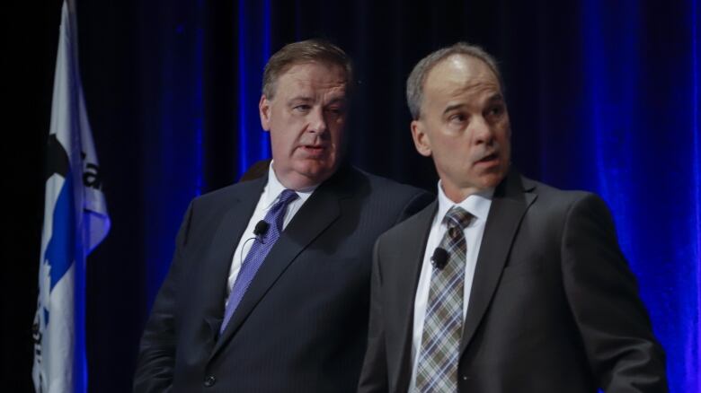 Two men in suits look off camera. 