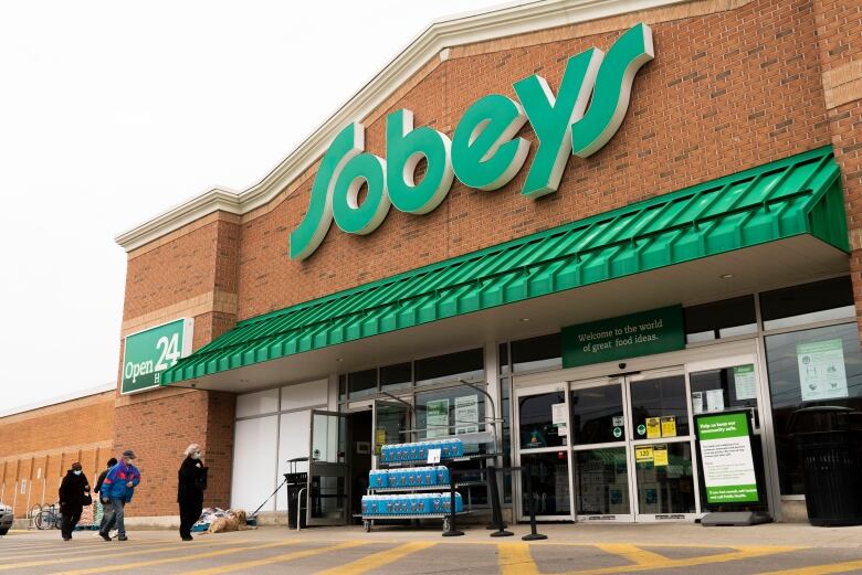 Four people are seen entering a grocery store.