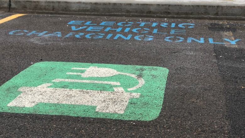 A stencil painted-space for an electric vehicle is show against the backdrop of a charger.