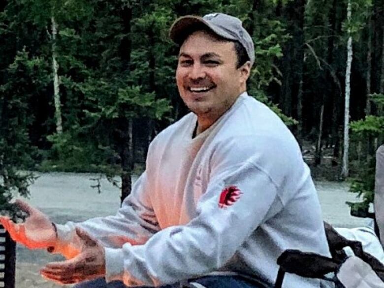 Man laughs while sitting in a camping chair.