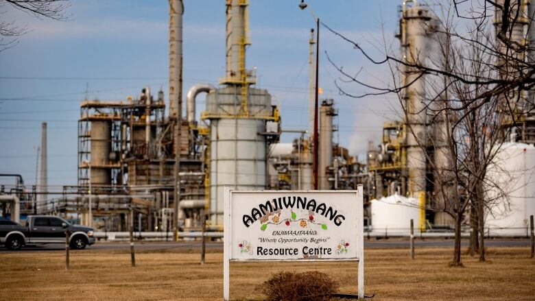 Chemical plants in the background of a sign that reads 