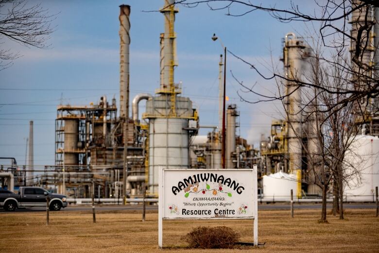 Chemical plants in the background of a sign that reads 