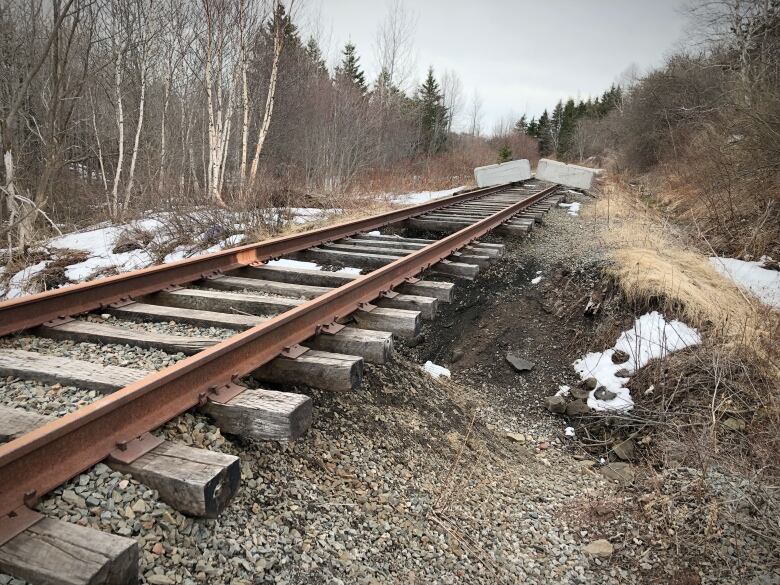 Image shows railway tracks with the gravel bed washed out underneath and concrete jersey barriers placed across the tracks.