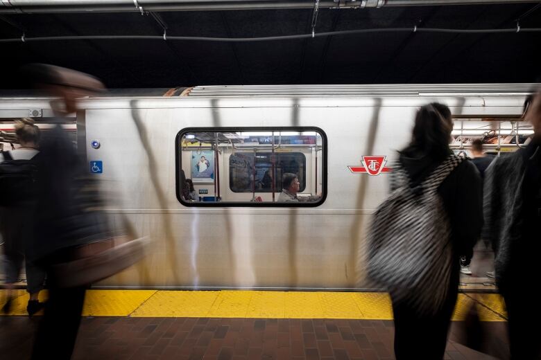 a subway train underground rushes by people