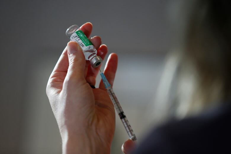 Hand holds a vaccine and needle.