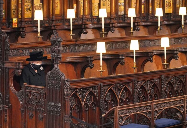 A woman in a black hat sits in a church pew.