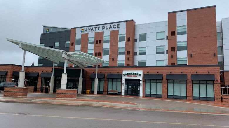 A large, multi-storey brick and metal building with a car port and sign, Hyatt Place, across the top.