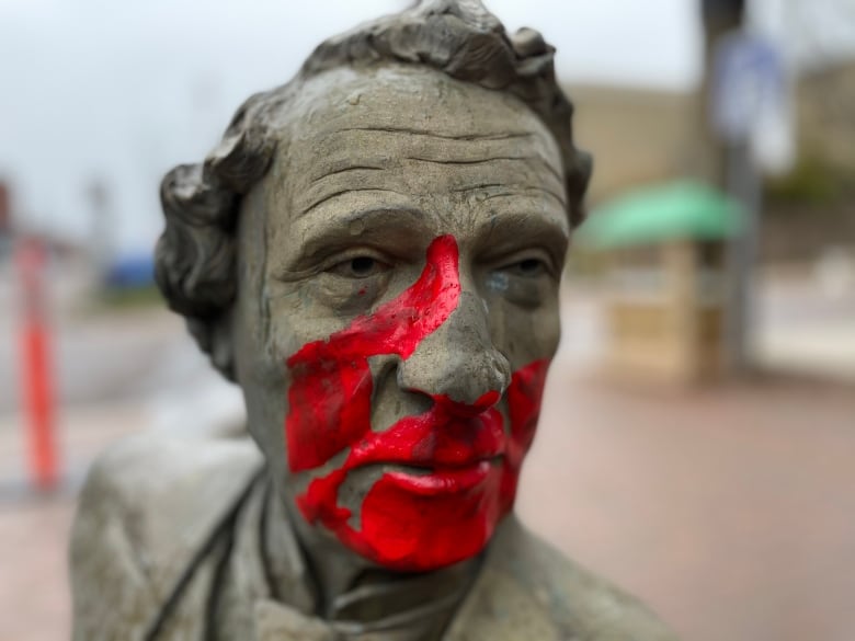 A red hand print marks the face of the bronze John A Macdonald.