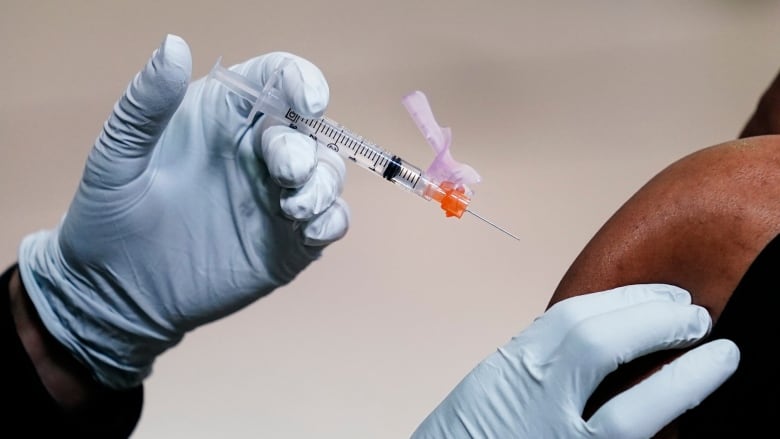 A member of the Philadelphia Fire Department administers a COVID-19 vaccine to a person at a vaccination site setup at a Salvation Army location in Philadelphia on March 26, 2021.