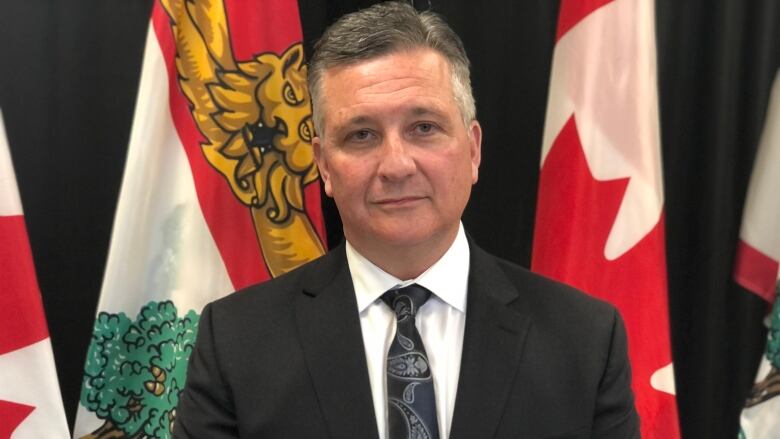 Malpeque MP Heath MacDonald standing in from of Canada and P.E.I. flags.