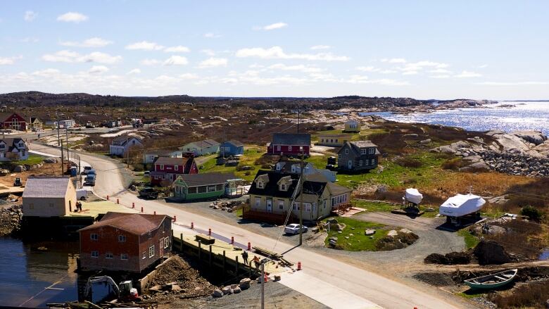 An aerial view of part of the Peggy's Cove village shows colourful houses against rolling hills and the sea