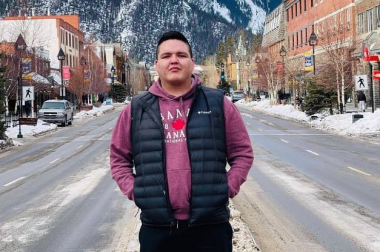 A man poses for a photo in front of a snowy mountain vista.