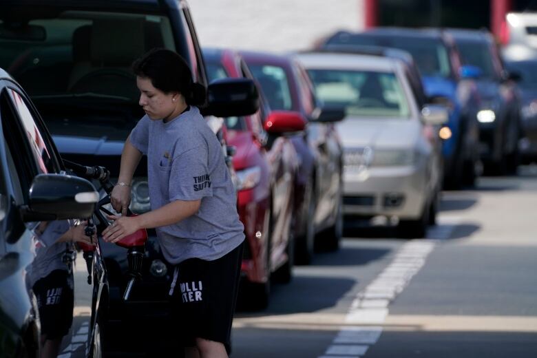 A customer pumps gas at Costco, as others wait in line, on Tuesday, May 11, 2021, in Charlotte, N.C. Gasoline futures are ticking higher following a cyberextortion attempt on the Colonial Pipeline, a vital U.S. pipeline that carries fuel from the Gulf Coast to the Northeast. (AP Photo/Chris Carlson)