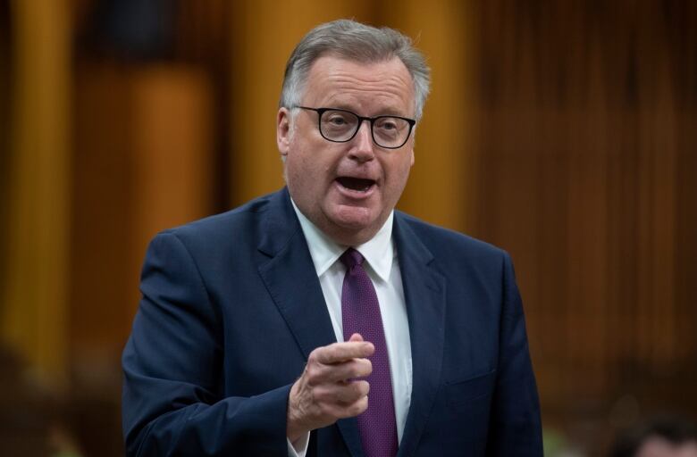 A man in a suit gestures while speaking.