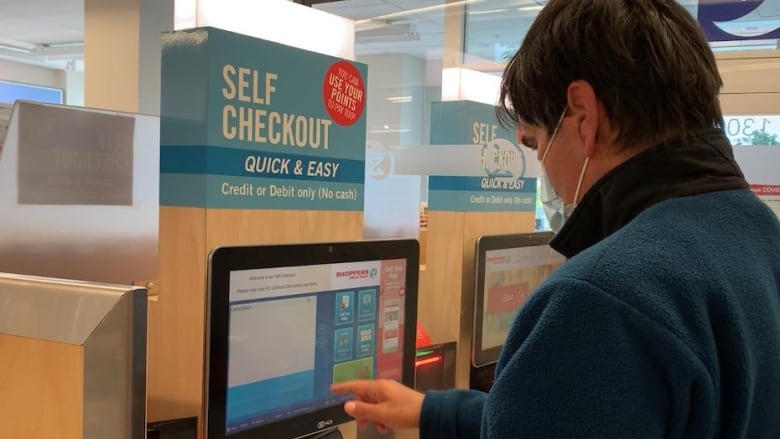 A man using self-checkout at Shoppers Drug Mart. 