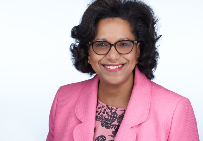 A Black health-care worker in a pink suit. 