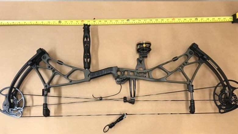 a close up image of a compound bow weapon on a table, looking down from above it. 