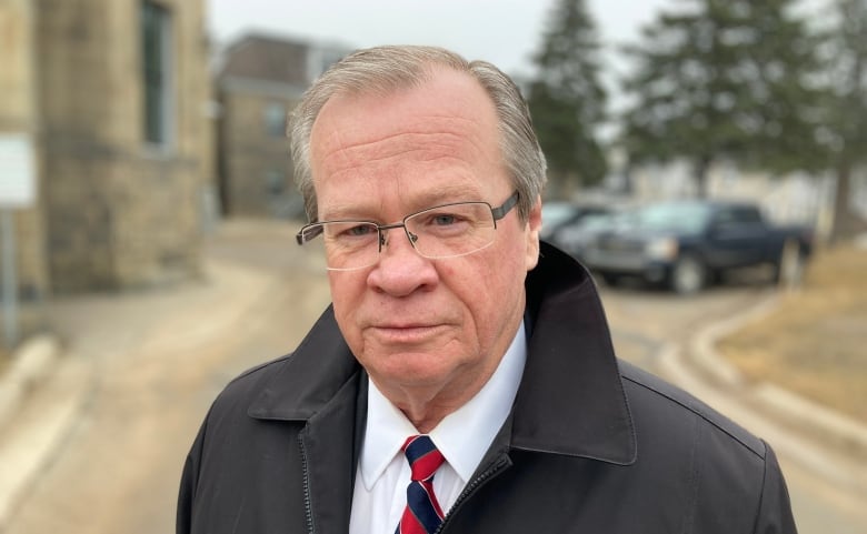 A man wearing a coat with a shirt and tie underneath.