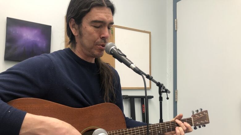 Musician Jay Gilday performing live playing an acoustic guitar.