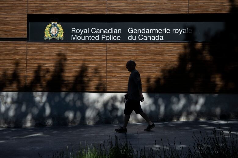 A man walks past a sign that reads 'Royal Canadian Mounted Police'.