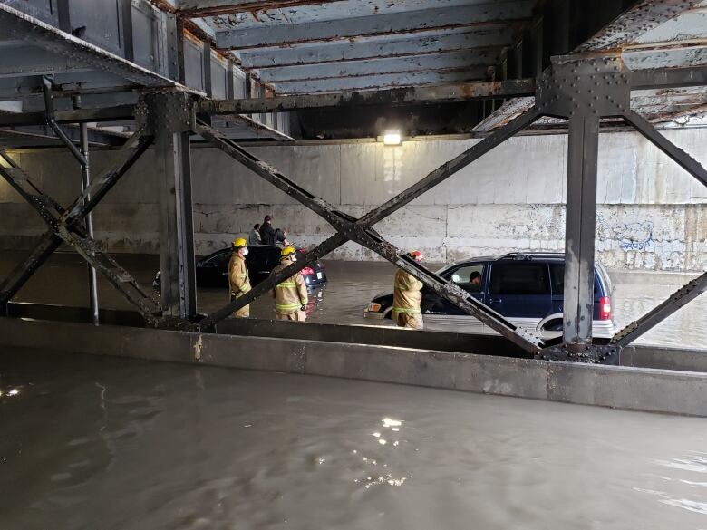 Firefighters rescue drivers from vehicles stuck in the Broad St. underpass after heavy rainfall. 