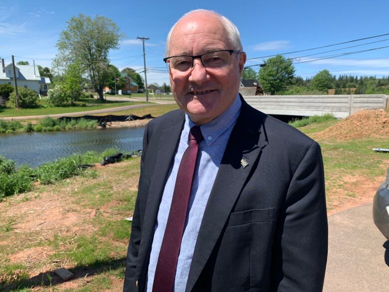 Man in suit standing in front of river