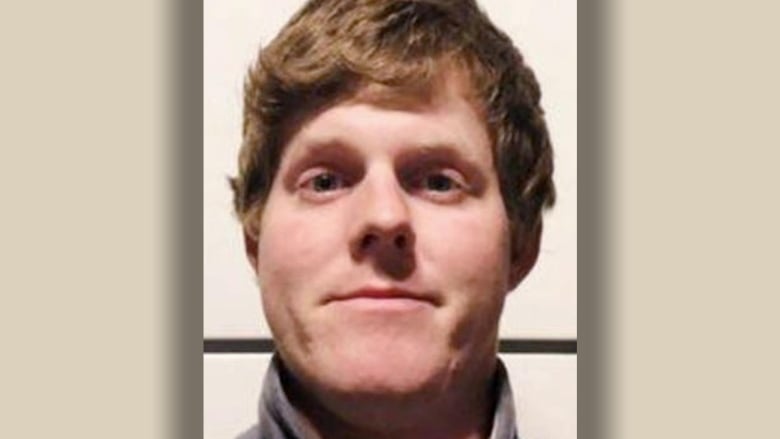 A close up of a man's face, showing his short, wavy reddish-blonde hair. He is smiling.